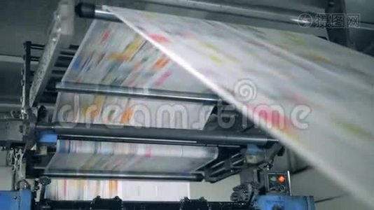 一台机器工作，在印刷设施中滚动印刷报纸。视频