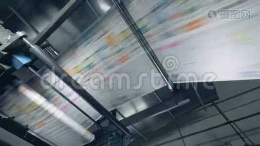 彩色报纸在印刷输送机上滚动，自动机器。视频
