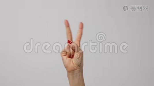女人举起两个手指，表示和平或胜利的象征或字母V。女人一只手举起两个手指视频