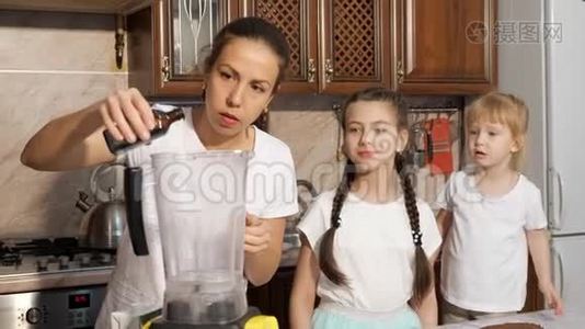 妈妈正在厨房里和她的女儿们用搅拌机做奶油。视频