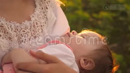 日落时分，一个小婴儿睡在母亲的怀里，慢镜头拍摄视频
