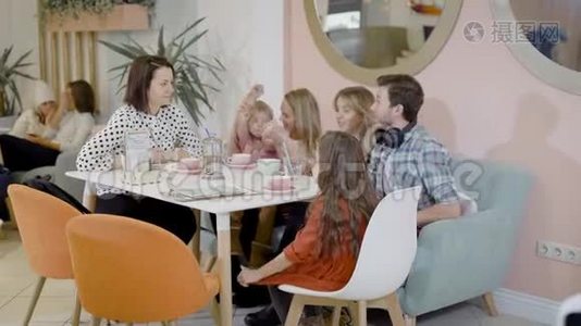 快乐的成年女人、男人和小孩坐在舒适的咖啡馆里，白天喝热巧克力视频