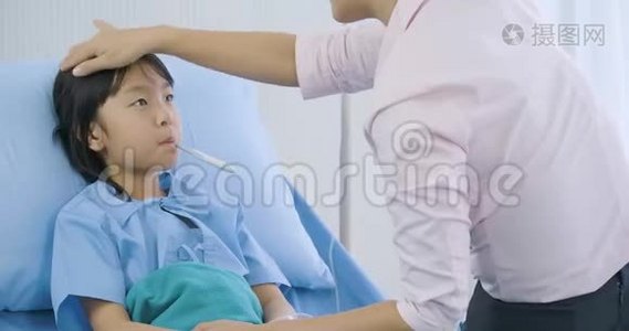 母亲在医院里测量她的小女儿的体温后看着体温计视频