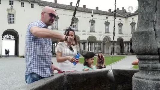 奥罗帕，比利亚，意大利-2018年7月7日：人们从银桶中喝银高山水，从石哥特面具中喝水视频