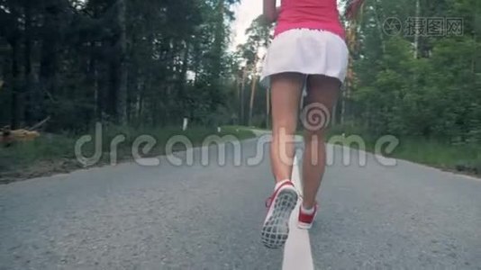 森林路上有一位年轻女士`腿沿着它慢跑。 蒸汽机，慢动作。视频