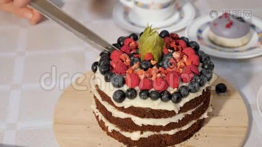 女人切一块生日自制的巧克力蛋糕，蛋糕上有奶油和海绵蛋糕，层层装饰着新鲜浆果视频
