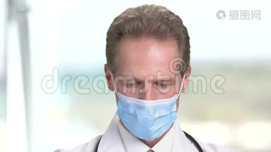 一个戴面具的医生闭上脸往下看。视频