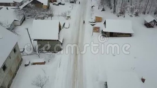 快速飞越喀尔巴阡村的一条公路。 鸟`雪覆盖的房子的视野。 冬季的乡村景观视频