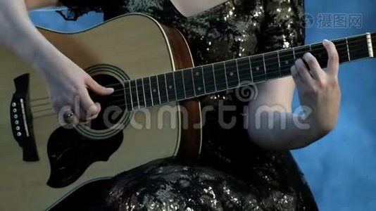 一个穿着晚礼服的女孩弹着六弦的吉他。 右手触弦，左手握弦视频