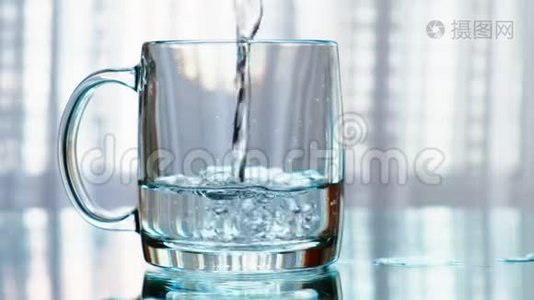 干净的饮用水被倒进杯子里。 慢动作。视频