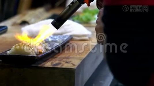 切夫的慢动作燃烧一条鱼，用吹嘴使寿司焦糖化视频