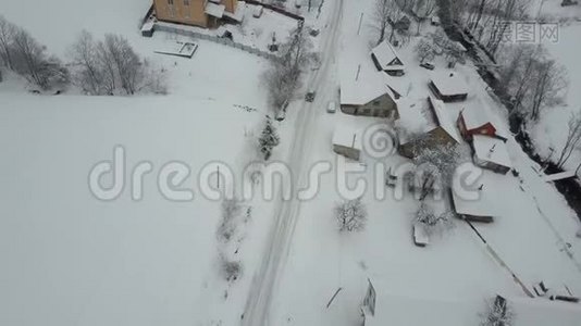 在喀尔巴阡村的冬季公路上行驶的一辆汽车上快速飞行。 鸟`雪覆盖的房子的视野。 农村视频