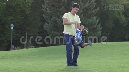快乐的亚洲父亲在草地上旋转他可爱的儿子视频