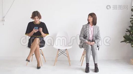 三个女商人希望在办公楼走廊的椅子上接受采访。视频