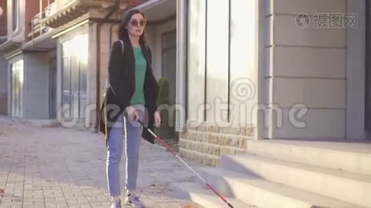 年轻的盲人带着一个带拐杖的背包，穿过城市的日光浴视频