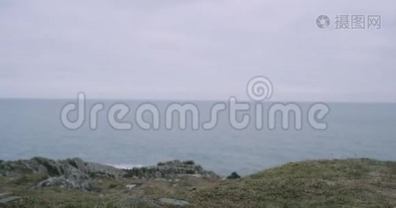 一名男子游客穿着棕色靴子在山顶海岸的特写细节，他欣赏海景。视频