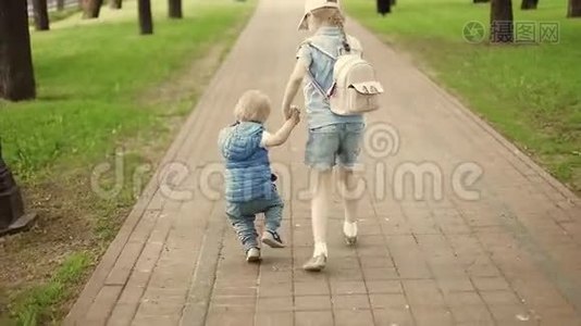姐姐牵着一个弟弟的手，在夏天的公园里到处跑。视频
