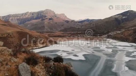 以史诗般的岩石和悬崖为背景，在冻结的山湖畔鸟瞰山坡和悬崖。视频