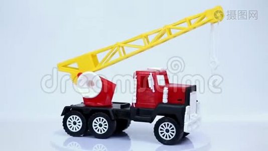 红色玩具起重机卡车与挂钩模型车旋转在白色背景。视频