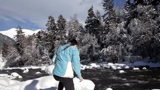 一个年轻的女孩走在森林附近。 冬季景观视频