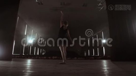 慢动作：穿黑色连衣裙的首席芭蕾舞演员表演旋转和优雅的舞蹈动作。 相机继续前进视频