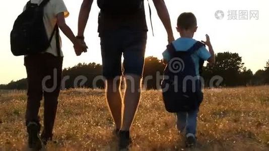 游客的幸福家庭：爸爸和他的两个儿子在日落时背着背包在大自然中行走。 的概念视频