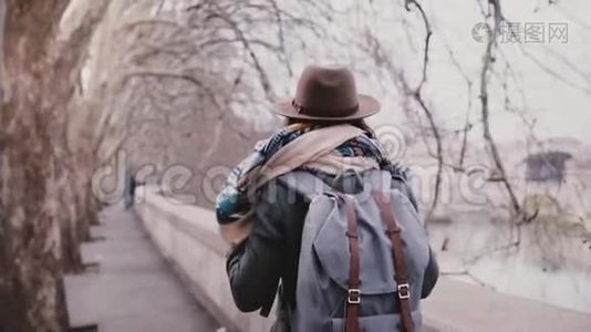 后景的女游客带着背包走在惊人的平面树河岸，在寒冷的深秋缓慢的运动。视频