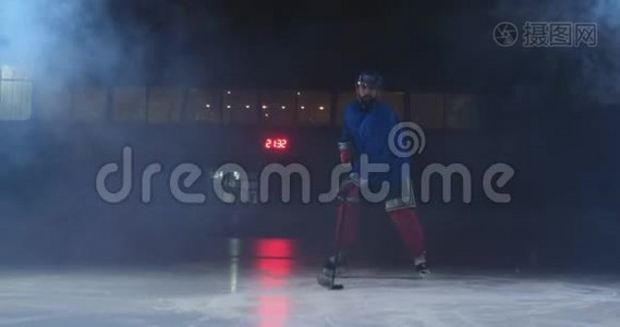 职业冰球运动员带着棍子和冰球在鲁达身上移动，穿着溜冰鞋和头盔在黑暗的背景和烟雾中移动视频