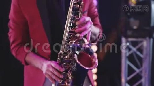 穿红色夹克的萨克斯演奏家在金色萨克斯管上演奏。 现场表演。视频