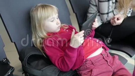 女儿和母亲正在平板电脑和手机上打字，等待飞机。视频