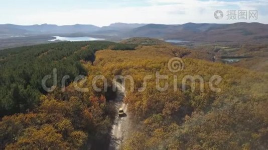 从空中俯瞰汽车在山上穿过森林。 秋天在美丽的山路上开车。 空中飞行视频