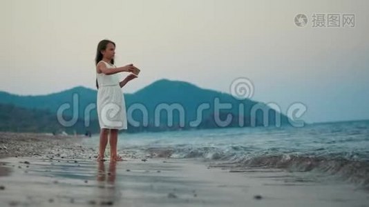 日落时分在海边的智能手机摄像头上摆姿势的小女孩视频