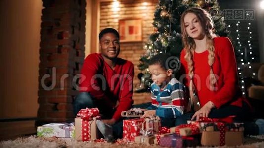 新年礼物中，一个幸福的家庭正坐在圣诞树`附近。视频
