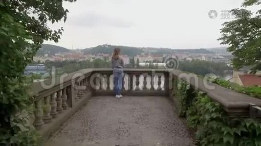 年轻女子从山上的阳台欣赏城市景色，镜头从后面移过来视频