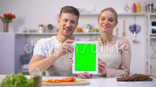一对幸福的情侣手持绿屏平板电脑，网上购物模板视频