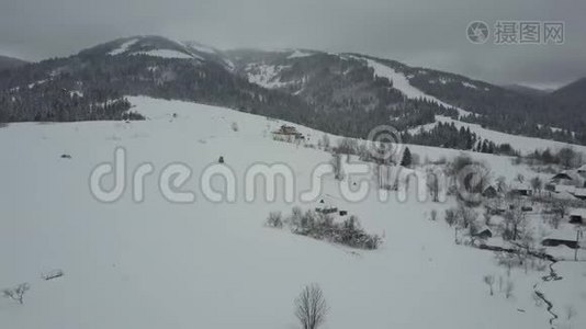 飞越喀尔巴阡山的一个村庄。 鸟`山上白雪覆盖的房子的视野。 乡村景观视频