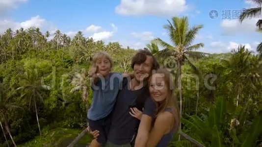 一个年轻的家庭在一个大平台上拍摄自拍，可以看到丛林视频