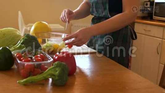 无法辨认的女人把蔬菜沙拉混合在透明的碗里。 厨房里的女人，适当的营养视频