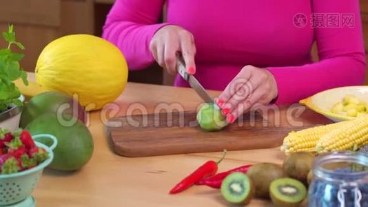 穿着粉红色上衣的女人在桌子上切着多汁的绿色猕猴桃视频