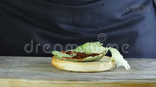 为一个汉堡提供半个面包，上面有一片生菜叶，上面浇上番茄酱视频