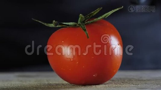 一个大番茄躺在一块木板上，背景是黑色的，厨师把一个番茄切成两块视频