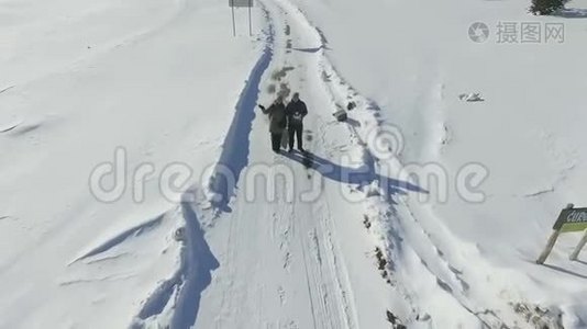 一对夫妇站在白雪皑皑的冬季道路上的鸟瞰图视频