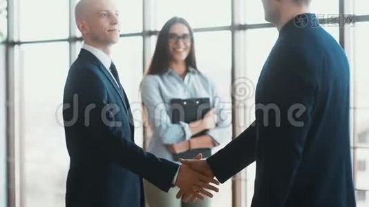 两位业务伙伴见面时握手.. 动作缓慢。 背景中漂亮的女秘书视频