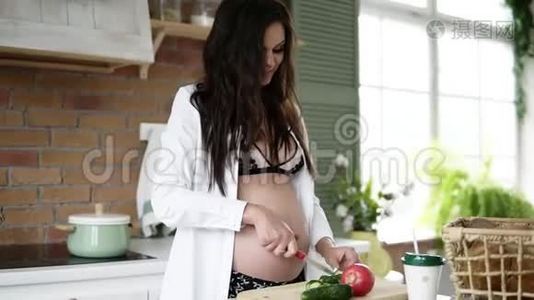 特写镜头，一个怀孕的白种人，长着深色头发，在家厨房里切蔬菜。 目标镜头视频