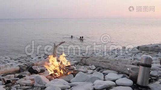 幸福的一家人在篝火旁的野生海滩上享受夏日日落。视频