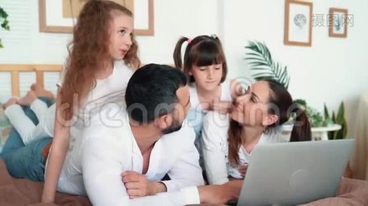 家庭幸福，父母和两个女儿在笔记本电脑上看电影，慢动作视频