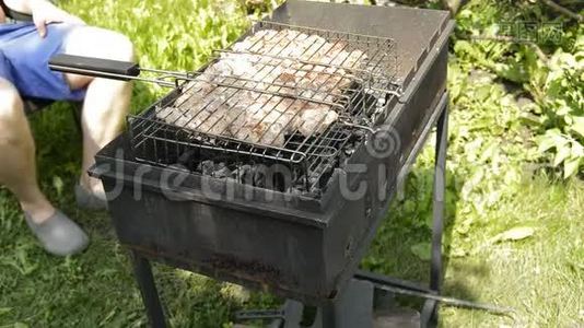 准备烤架上的生肉烧烤.. 在阳光明媚的夏日野餐时，他烤猪肉，转烤架视频