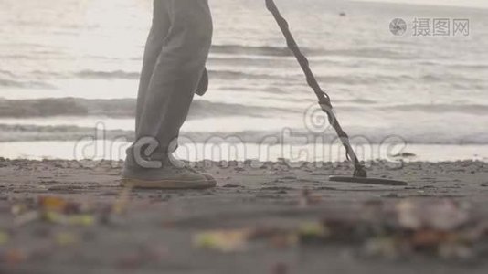 人类正在用金属探测器扫描海滩上的沙子，并开始在海岸线上挖掘。视频
