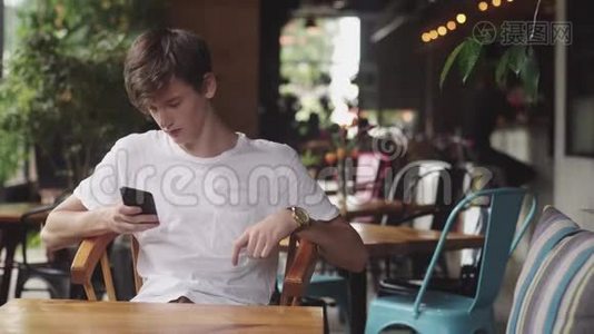 年轻人用手机上网，方便触摸，在咖啡馆发送短信。 帅哥在里面聊天视频