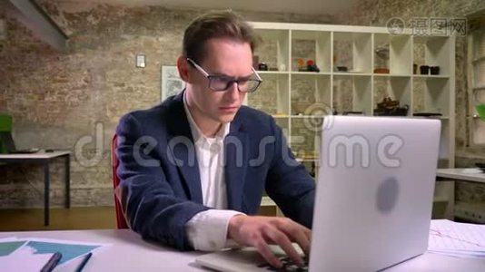 喜欢白种人的男人在室内笔记本电脑附近的工作场所展示胜利者的手势视频